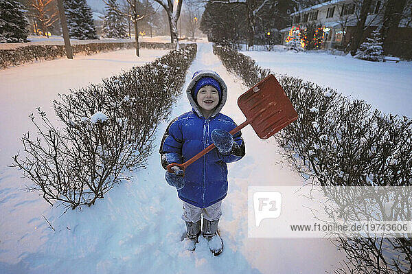 Young boy shoveling snow in front of his house; Lincoln  Nebraska  United States of America