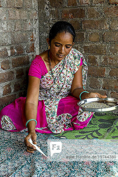 Adivasi woman sticking beads onto a sari in a village in Narmada district  Gujarat  India  Asia