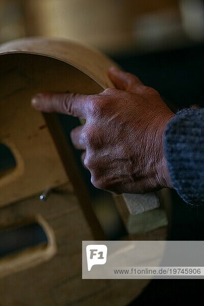 Luthier handwerklichen Geigenbauer faltige Hand halten schnitzen sculpt Meißel Rippen eines neuen klassischen Modells Cello in der Werkstatt Cremona Italien  selektiver Fokus  Bokeh