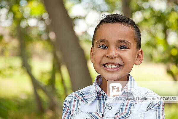 Lächelnder junger hispanischer Junge im Freien unter den Bäumen