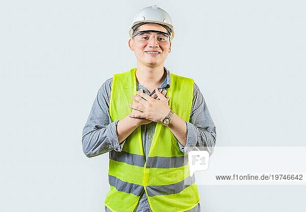 Porträt eines jungen Ingenieurs mit dankbarer Geste. Hübscher dankbarer Ingenieur mit Händen auf der Brust isoliert