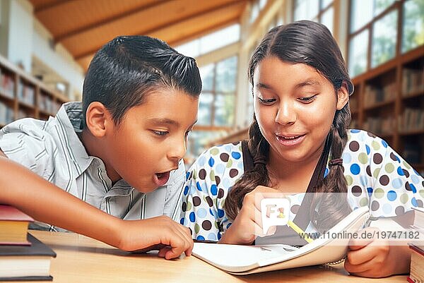 Hispanische Schulkinder machen gemeinsam Hausaufgaben in der Bibliothek