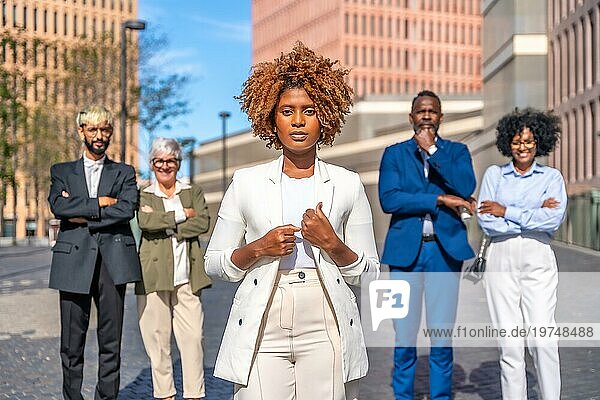 Frontalfoto einer afrikanischen Geschäftsfrau  die ernsthaft neben ihren Kollegen steht