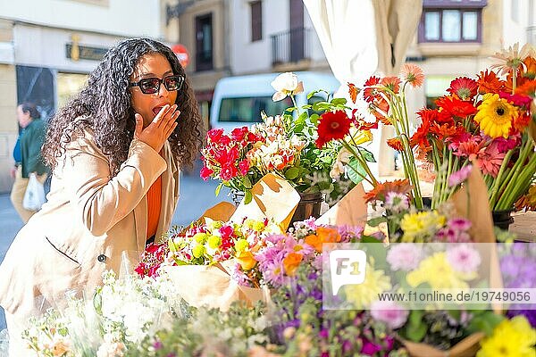 Überrascht Frau kauft Blumen in einem Marktstand während eines sonnigen Wintertages in der Stadt