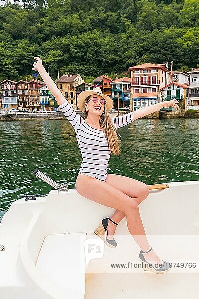 Vertikales Porträt einer schönen und sinnlichen Frau  die auf einem Boot in der Nähe einer Küstenstadt die Freiheit feiert