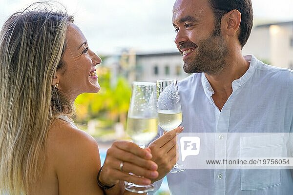 Romantisches Paar lächelt und feiert seine Flitterwochen mit Champagner auf einer Hotelterrasse