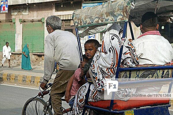 Fahrradrikscha mit altem Fahrer  der eine Familie im städtischen Nahverkehr in Mathura  Indien  befördert  Asien