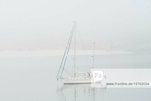 Segelboot  Segelschiff  Yacht mit gesenkten Segeln vor Anker in Strandnähe bei schlechter Sicht durch dicken Nebel  dichten Dunst