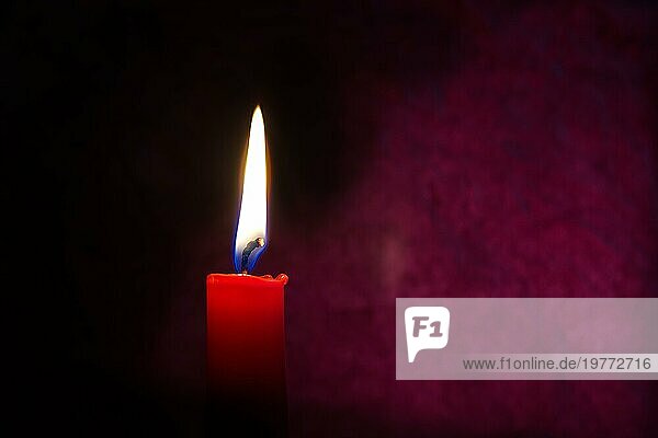 Einzelne rote Kerze brennt allein in der dunkelroten Hintergrund. Konzeptuelles Bild symbolisieren Frieden  Liebe  Hoffnung oder Geduld mit freiem Kopierraum