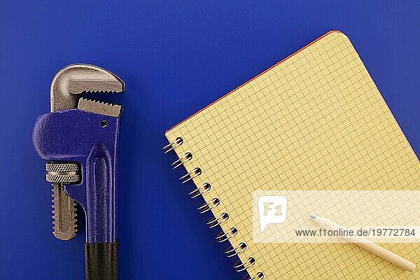 Verstellbare Rohrzange und Draht gebunden offenes Notizbuch auf blauem Hintergrund  Sanitär und mechanische Schätzung Konzept mit freien Raum für Text kopieren