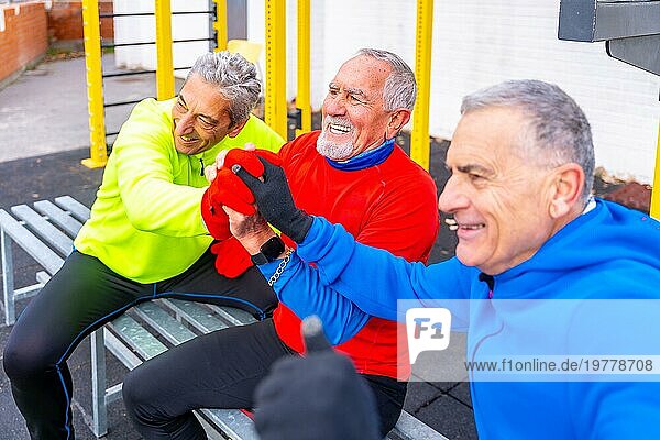 Ältere Sportfreunde reichen sich im Winter auf einem Sportplatz im Freien die Hände
