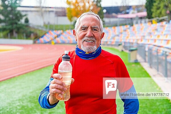 Stolzer alter Mann mit einer wiederverwendbaren Wasserflasche nach einem Training in der Leichtathletik