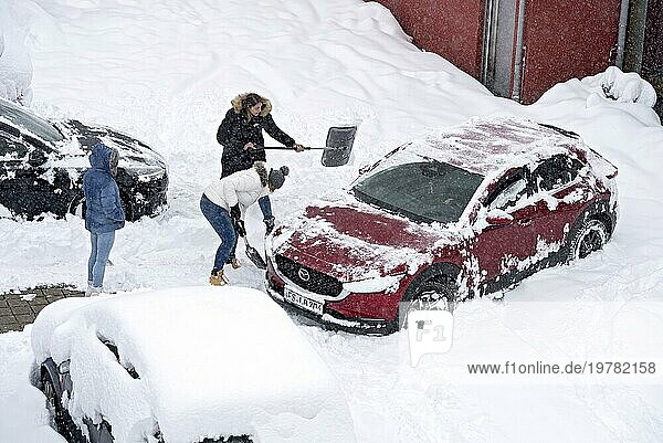 Frauen schaufeln Schnee auf Parkplatz  Auto  PKW  eingeschneit  Neuschnee  starker Schneefall  Schneemassen  Schneechaos  Schneeschaufel  Wintereinbruch  Marzling  Freising  Oberbayern  Bayern  Deutschland  Europa