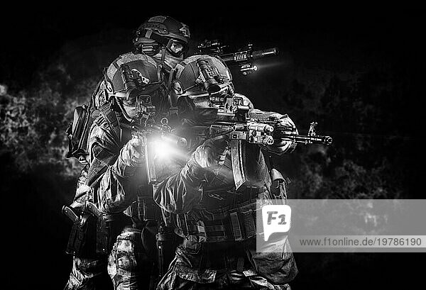 Amerikanische Soldaten in Kampfmunition mit Waffen in den Händen  die mit Laserzielgeräten ausgestattet sind  befinden sich in Schlachtordnung. Gemischte Medien