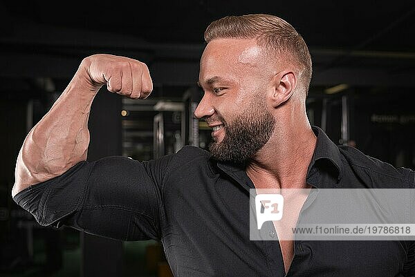 Stylish Mann in einem BusinessAnzug posiert in der Turnhalle. Business und Bodybuilding Konzept. Sportliche Aktivitäten. Gemischte Medien