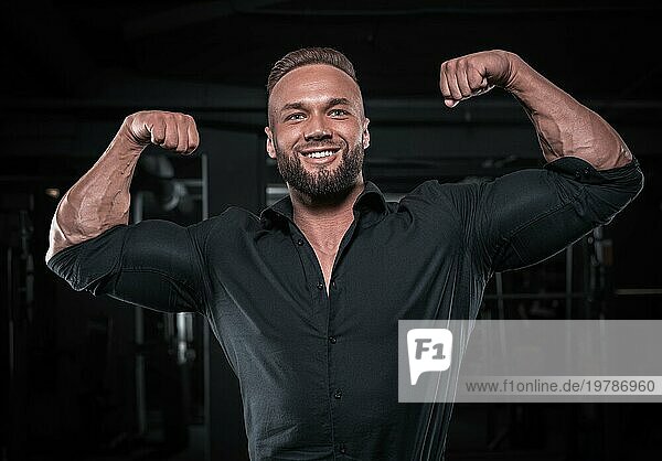Stylish Mann in einem BusinessAnzug posiert in der Turnhalle. Business und Bodybuilding Konzept. Sportliche Aktivitäten. Gemischte Medien