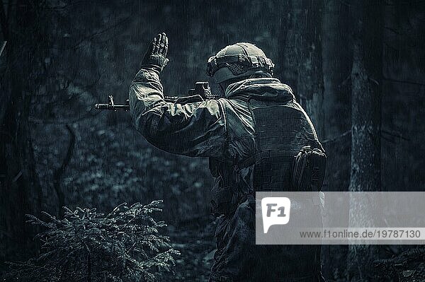 Porträt eines Soldaten  der durch den Wald geht. Er hebt die Hand  um seinen Partner vor der Gefahr zu warnen. Grenzschutz Konzept. Rückansicht