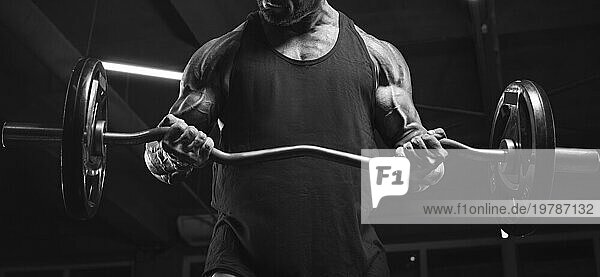 Bild eines kraftvollen Athleten  der eine Langhantel in einem Fitnessstudio hebt. Bizeps pumpt. Fitness und Bodybuilding Konzept