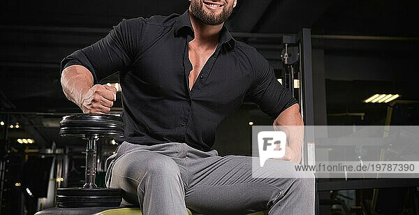Stilvoller Mann in einem BusinessAnzug trainiert im Fitnessstudio. Business und Bodybuilding Konzept. Sportliche Aktivitäten. Gemischte Medien