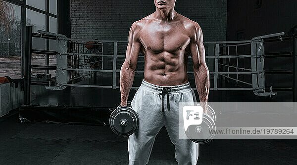 Hübscher junger Mann beim Training mit Hanteln im Fitnessstudio. Schultern pumpen. Fitness und Bodybuilding Konzept. Gemischte Medien