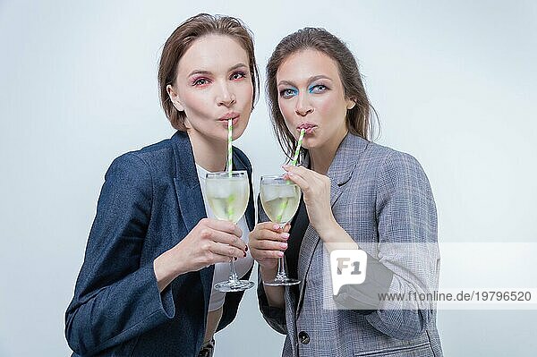 Porträt von zwei Geschäftsfrauen in Jacken mit Gläsern in ihren Händen. Konzept zur Feier erfolgreicher Geschäftsabschlüsse.