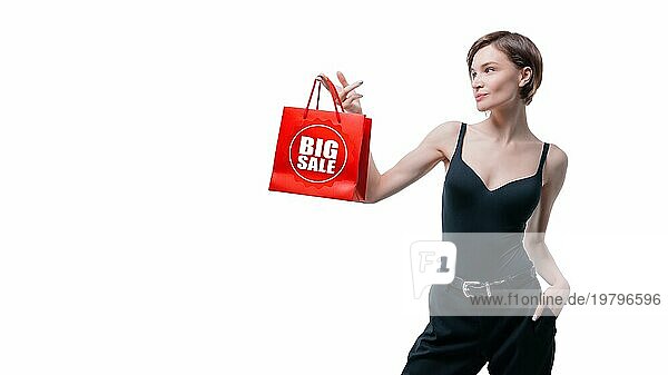 Schöne junge Frau hält ein rotes Paket in ihrer Hand. Shopaholics Konzept. Ausgeben. Geschenke für die Feiertage. Schwarzer Freitag. Einkaufszentren