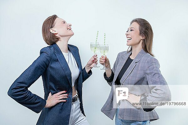 Porträt von zwei Geschäftsfrauen in Jacken mit Gläsern in ihren Händen. Konzept zur Feier erfolgreicher Geschäftsabschlüsse.