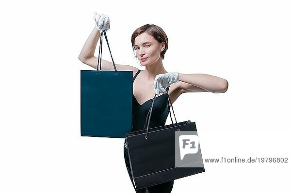 Ein elegantes großes Mädchen mit weißen Handschuhen zeigt ein schwarzes Luxuspaket. Das Konzept des sicheren Einkaufens während einer Pandemie