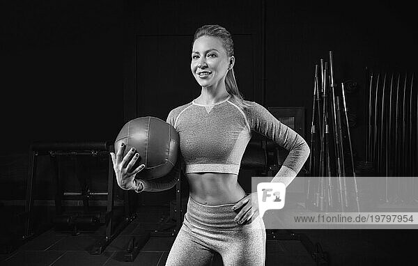 Charmante Blondine posiert im Fitnessstudio mit einem Fitnessball. Vorderansicht. Das Konzept von Sport  Bodybuilding  Fitness.