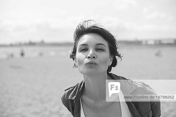 Porträt einer Frau  die einen Kuss in die Kamera schickt. Windiges Wetter. Fröhlichkeit  Freiheit und Sorglosigkeit. Tourismuskonzept