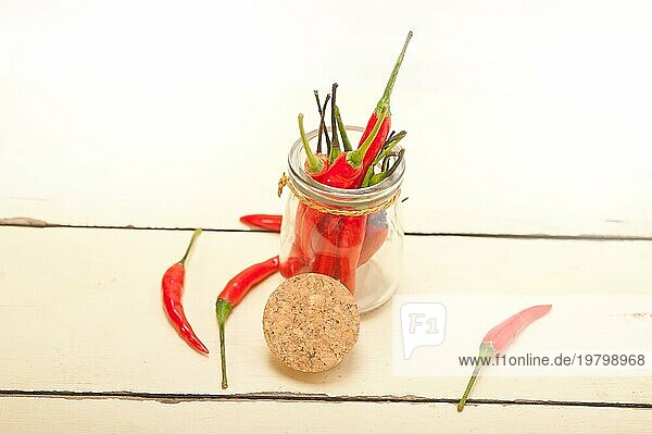 Rote Chilischoten in einem Glasgefäß auf einem rustikalen Tisch aus weißem Holz  Food photography  Food photography  Food photography