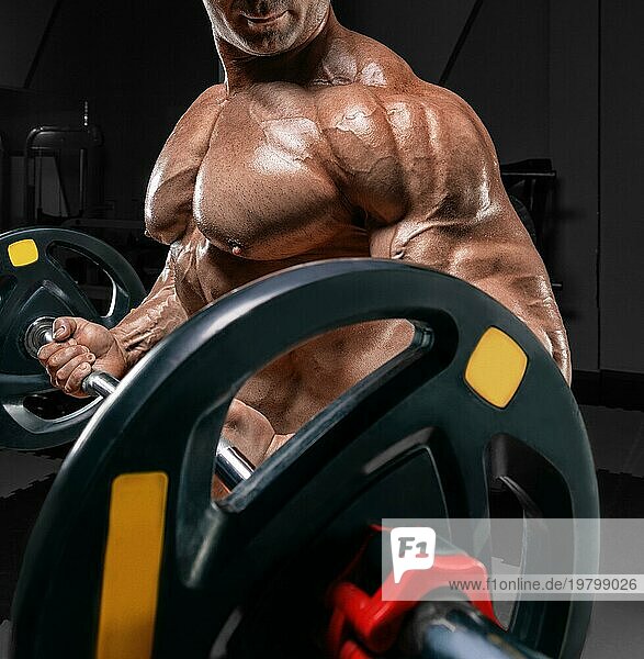 Kräftiger Bodybuilder trainiert in einem Fitnessstudio mit einer Langhantel. No Name Porträt. Bodybuilding Konzept.