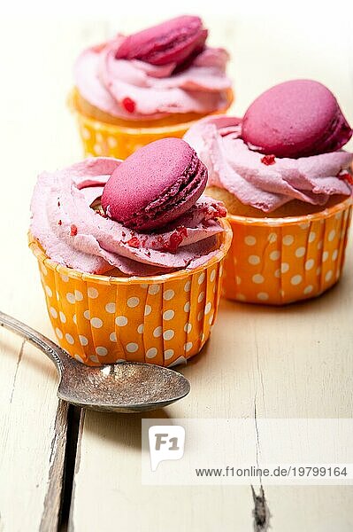 Frischer rosa Beerencremecupcake mit Makrone oben auf rustikalem Holztisch  Foodfotografie Foodfotografie  Food photography  Food photography