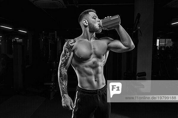 Porträt eines Sportlers  der aus einem Shaker im Fitnessstudio trinkt. Bodybuilding und Fitness Konzept.