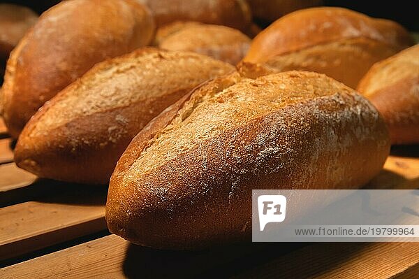 Frisches  knuspriges  heißes  leckeres  handwerklich hergestelltes Brot. Viele Brote liegen auf einer Holzpalette