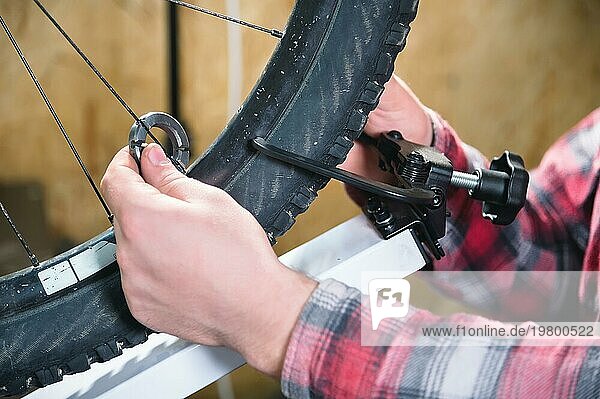 Nahaufnahme von Männerhänden mit einem speziellen Schraubenschlüssel auf einem Ständer in der Werkstatt  die die Speichen des Rades festziehen  um das Schlagen der Felge zu verhindern