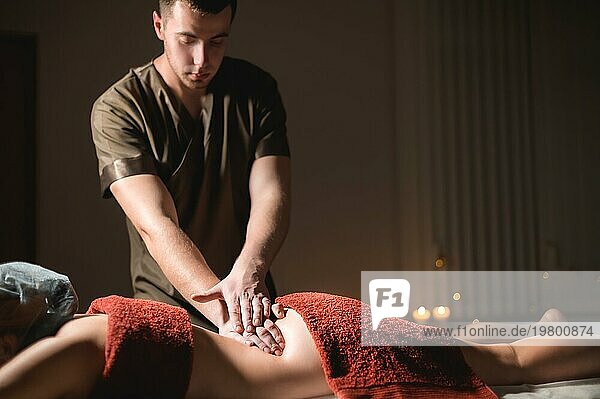 Kosmetologie und Physiotherapie. Professionelle Massage auf den unteren Rücken einer Frau wird von einem Masseur Mann gemacht. Konzept der manul Therapie und Massage Spabehandlungen