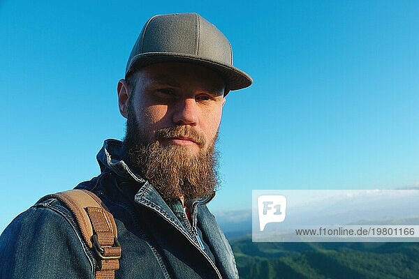 Porträt eines bärtigen stilvollen Reisenden mit einer Mütze vor blauem Himmel. Zeit zu reisen Konzept