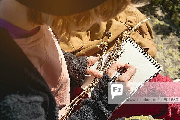 Mädchen Maler zeichnet einen Bleistift in einem Notizbuch auf die Natur in den Bergen. Freie Kreativität und Freiberuflichkeit
