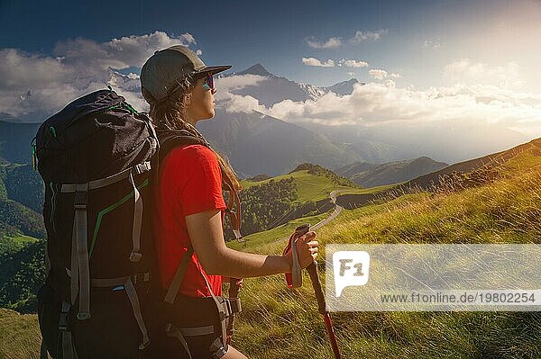 Frau Tourist jungen kaukasischen Walking bergauf an einem sonnigen Tag unter Sonnenlicht. Schöne Aussicht auf die Berglandschaft. Attraktive Trekking Sportlerin