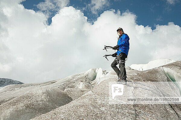 Reisende mit Mütze und Sonnenbrille in den schneebedeckten Bergen auf dem Gletscher stehend. Reisender in einer natürlichen Umgebung