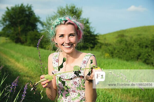 Porträt eines jungen  glücklich lächelnden Mädchens in einem Baumwollkleid mit einem Strauß Wildblumen