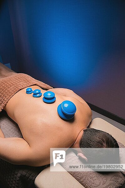 Vakuum Gummisauger für Schröpftherapie auf dem Rücken eines nackten Mannes. Massage im Spa  medizinische Behandlung für den Rücken. Revitalisierende und entspannende Massage  Fitnessbehandlungen