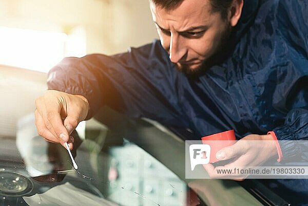 Close up Autoglaser Arbeiter Befestigung und Reparatur Windschutzscheibe oder Windschutzscheibe eines Autos in Auto Service Station Garage