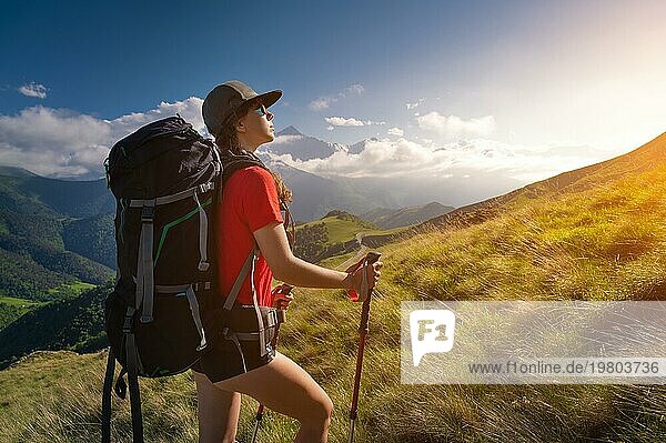 Frau Tourist jungen kaukasischen Walking bergauf an einem sonnigen Tag unter Sonnenlicht. Schöne Aussicht auf die Berglandschaft. Attraktive Trekking Sportlerin