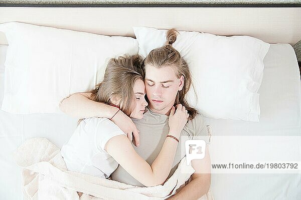 Ein junges Paar moderner Männer und Frauen schläft in ihrem weißen Bett in einer Umarmung. Das Konzept einer jungen modernen Familie und Schlafprobleme