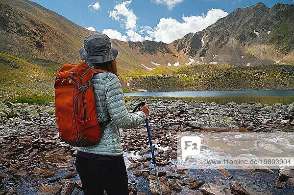 Rückansicht  junge Frau genießt Bergsee  Tourist schaut in die Ferne auf felsige Gipfel des Berges  Sommerurlaub Konzept