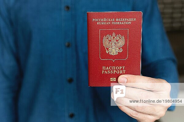 Nahaufnahme der Hand eines Mannes in einem Hemd  die einen ausländischen Pass hält  das Konzept der Vorbereitung auf einen Urlaub