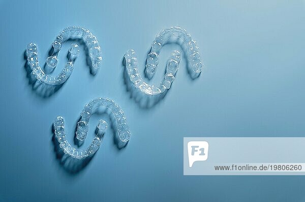 Unsichtbare Kunststoff Glätteisen liegen in einem Muster einander gegenüber  Platz für Text für eine Zahnklinik