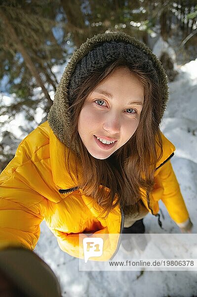 Junge kaukasische schöne Frau lächelnd. Taking a selfie Foto mit einer Kamera im Winter  in einem verschneiten Wald. Mädchen im Freien. Spaziergang im Park
